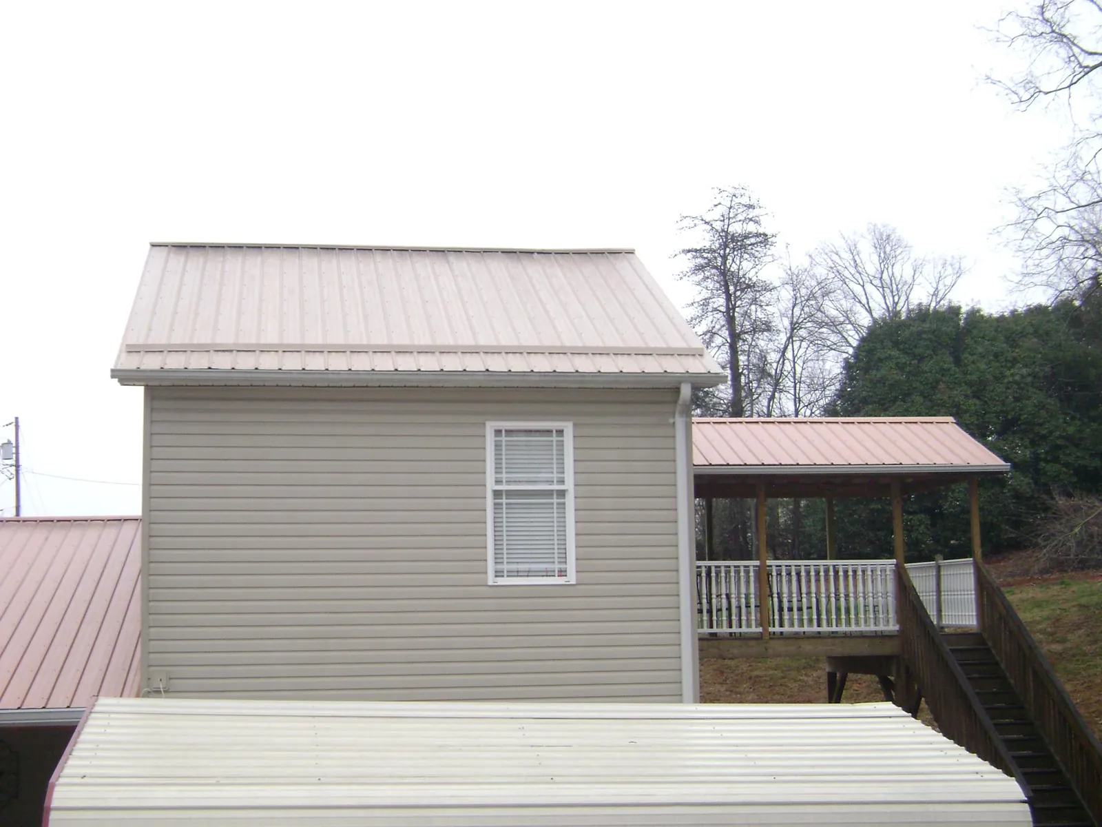 Tan metal roofs on a two story addition and attached porch, from a Roof Replacement job in Masontown