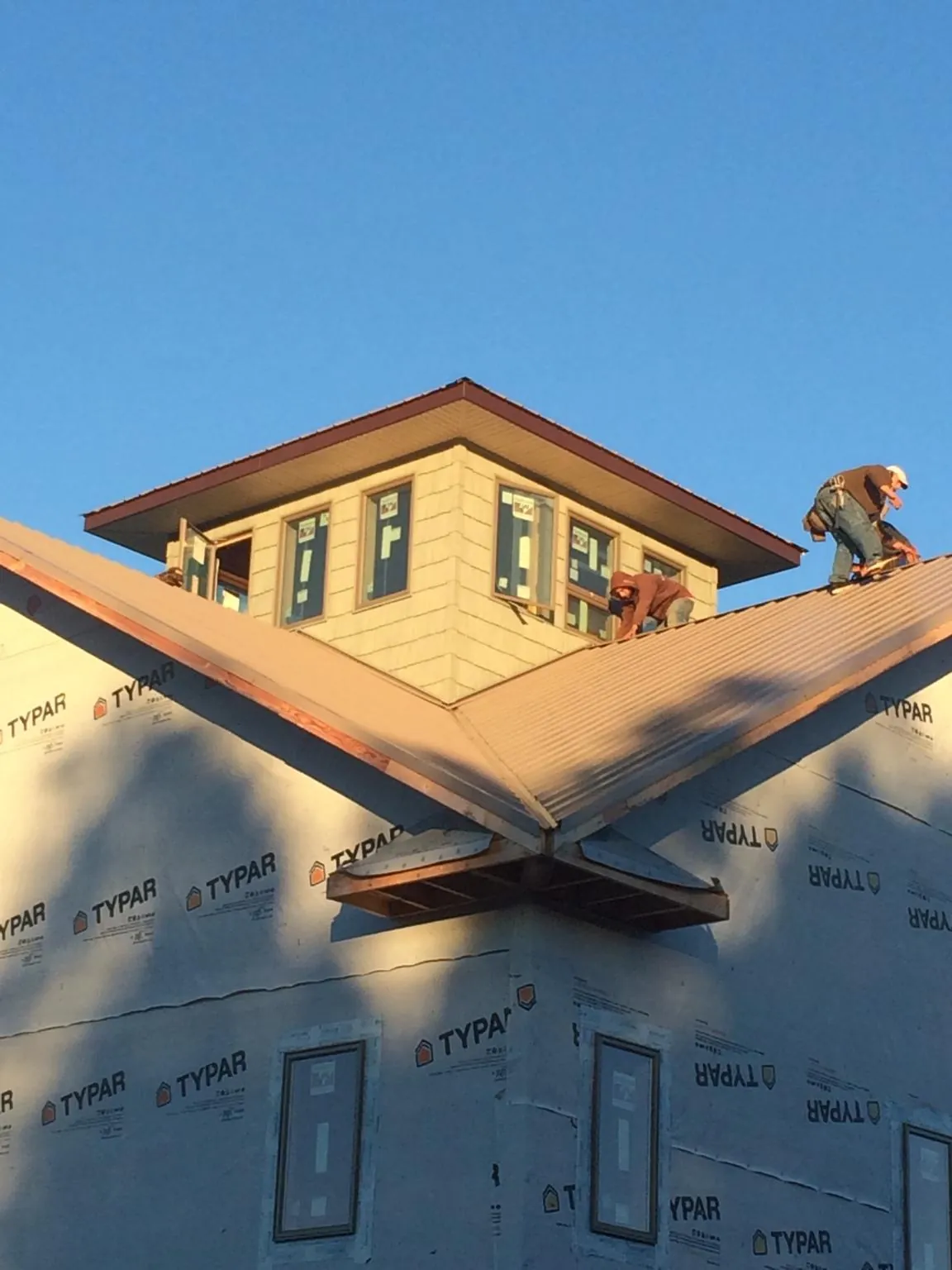 Roofers working around a rooftop cupola on a new metal roof at sunset — Roof Waterproofing in Masontown by Roofing Brothers
